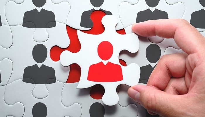 Selecting right people for organization's success. Think different and unique concept.
Putting last jigsaw puzzle piece with red businessperson.
